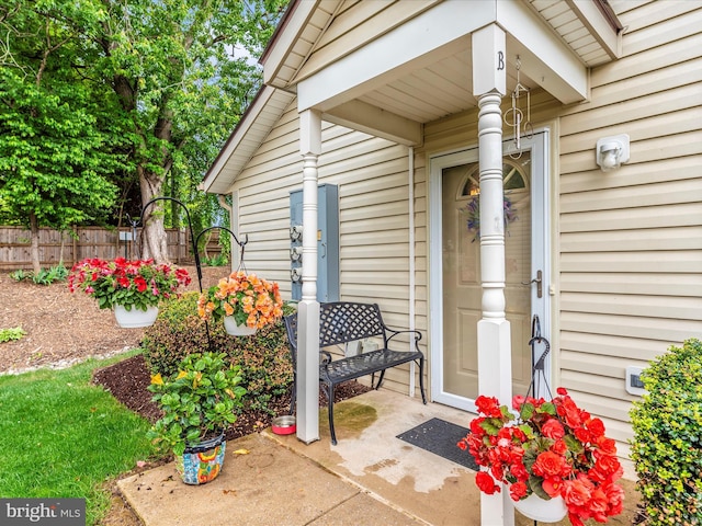 view of exterior entry with fence and a porch