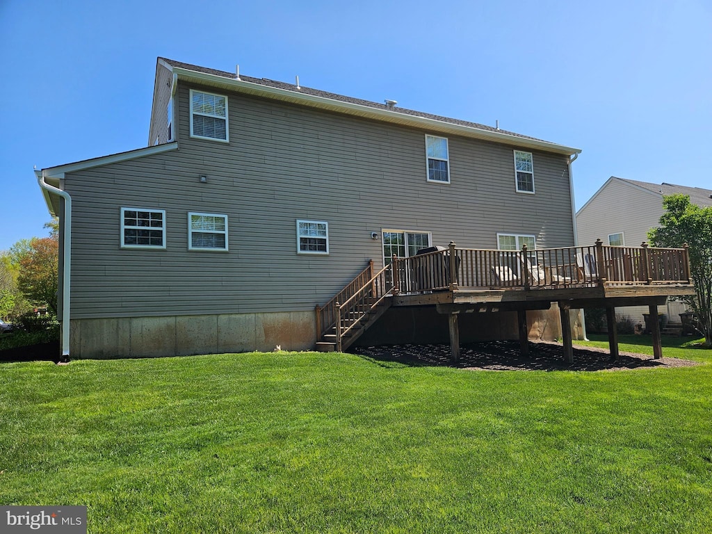 back of property with a yard, a deck, and stairs