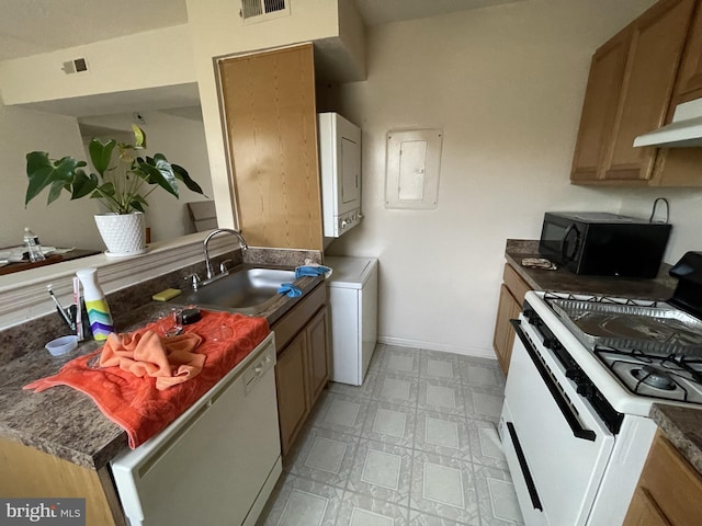kitchen with visible vents, white appliances, light floors, stacked washing maching and dryer, and a sink