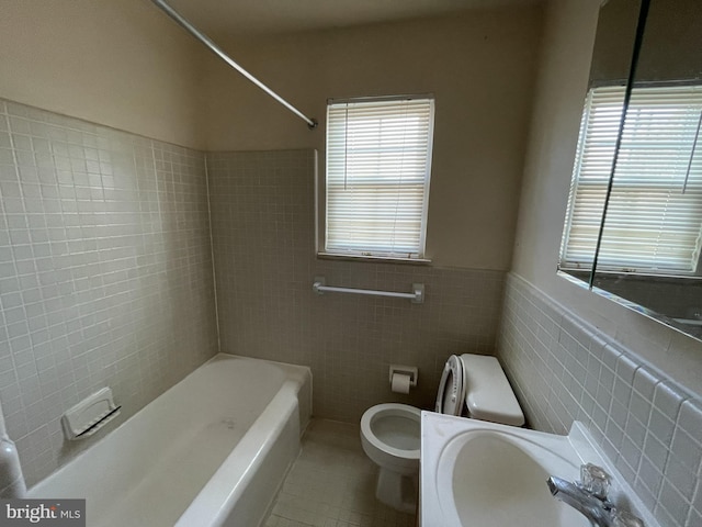 full bathroom featuring tile walls, tile patterned flooring, a wainscoted wall, toilet, and bathing tub / shower combination