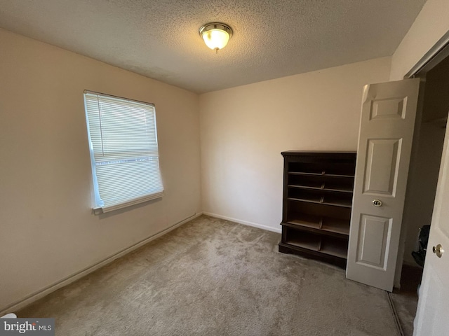 carpeted spare room featuring baseboards and a textured ceiling