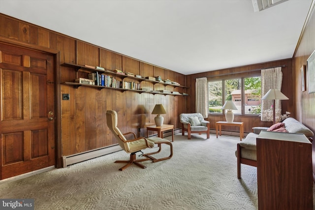 sitting room featuring visible vents, baseboard heating, a baseboard radiator, wooden walls, and carpet