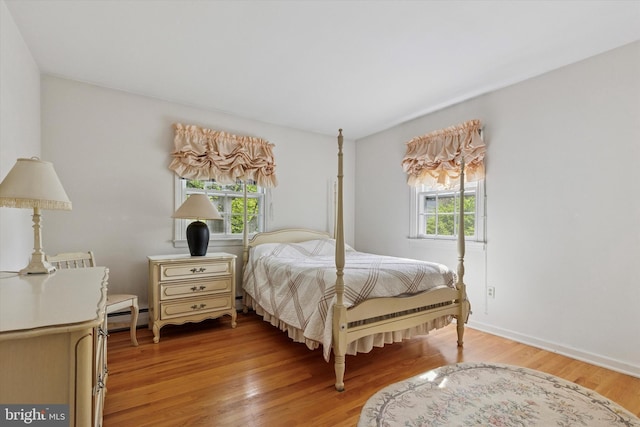 bedroom with baseboards, light wood-style flooring, and a baseboard radiator
