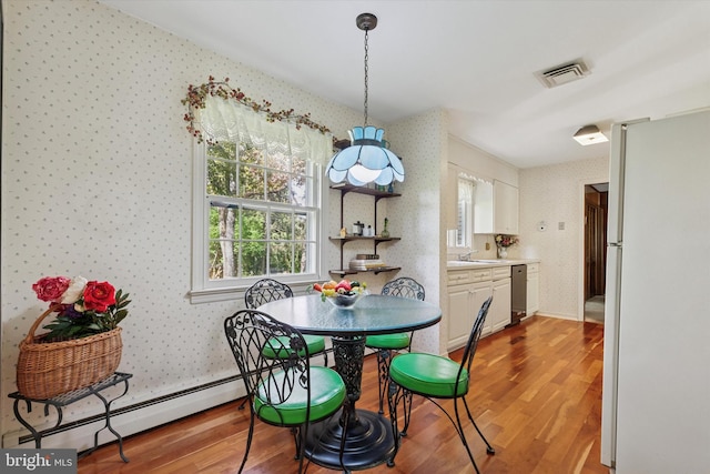 dining space with wallpapered walls, visible vents, baseboard heating, and wood finished floors