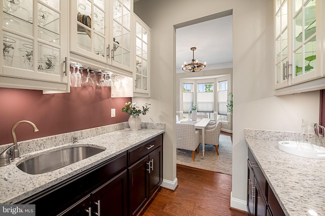 6354 Islington St, Middle River, MD 21220 - kitchen with a sink, dark wood-style flooring, dark brown cabinetry, light stone countertops, and glass insert cabinets
