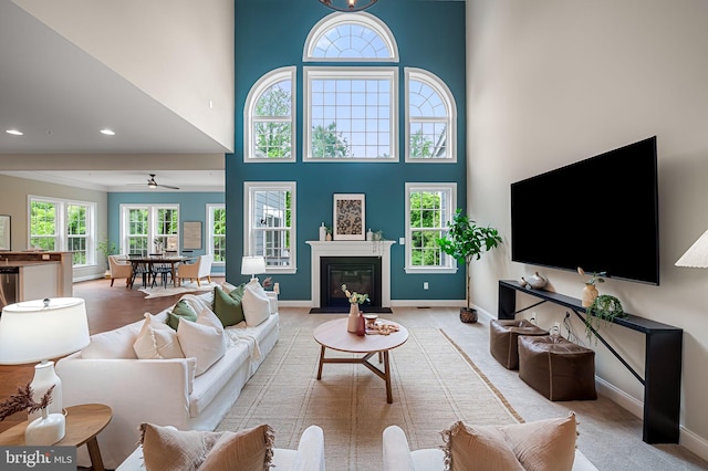 6354 Islington St, Middle River, MD 21220 - living room with a towering ceiling, baseboards, a ceiling fan, a fireplace with flush hearth, and light carpet