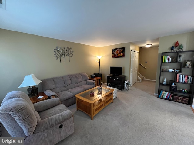 living room featuring stairway, baseboards, visible vents, and light colored carpet