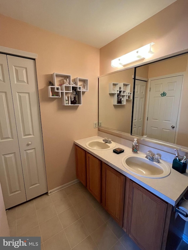 full bathroom featuring double vanity, baseboards, a sink, and tile patterned flooring