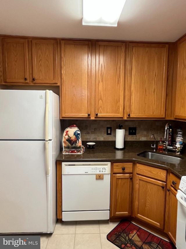 kitchen with decorative backsplash, white appliances, brown cabinets, a sink, and light tile patterned floors