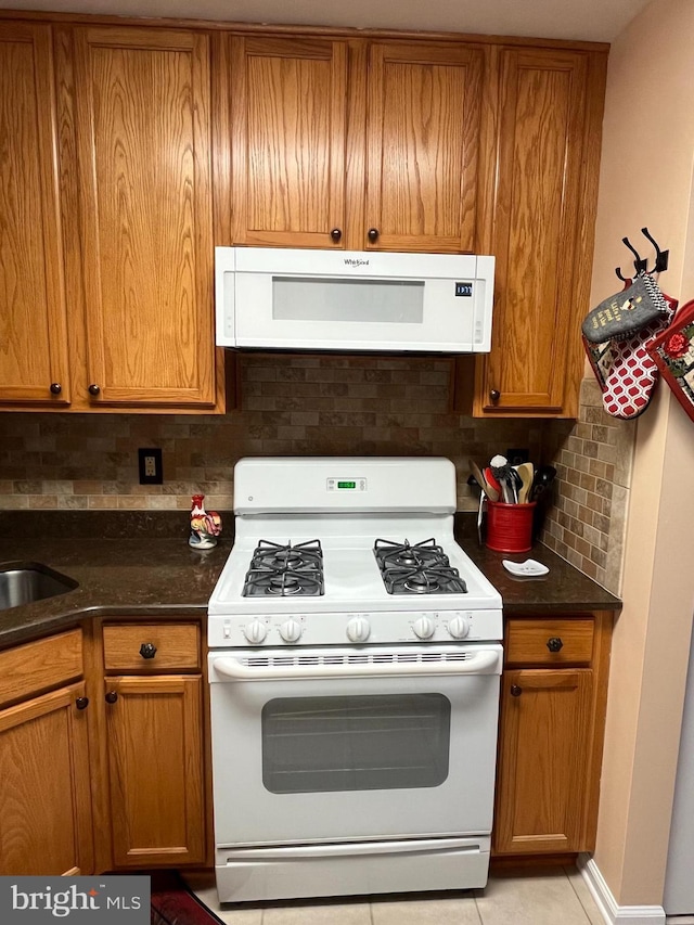 kitchen with a sink, brown cabinetry, range hood, tasteful backsplash, and white range with gas cooktop