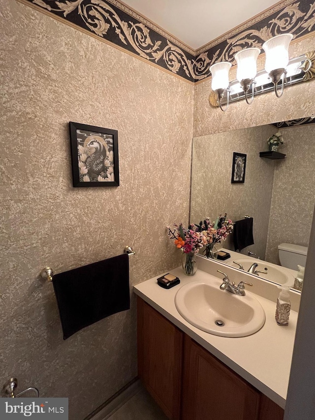 bathroom with toilet, a notable chandelier, and vanity