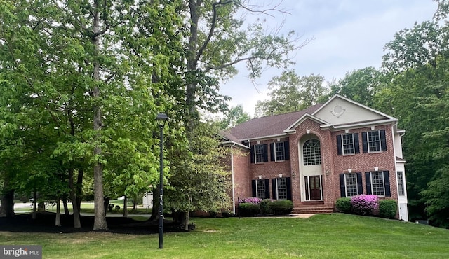 colonial home with brick siding and a front lawn