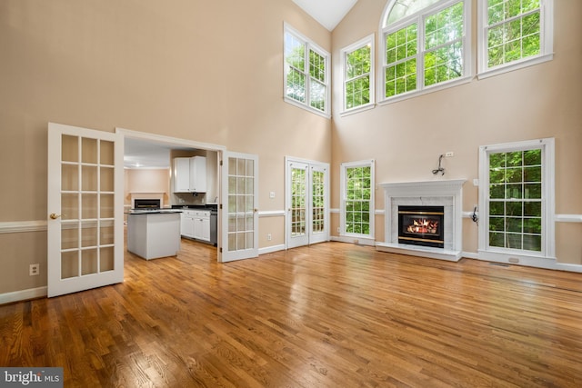12850 Salmon Run Ct, Manassas, VA 20112 - unfurnished living room with light wood finished floors, a towering ceiling, and french doors