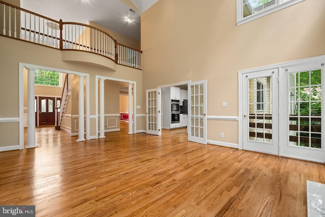 12850 Salmon Run Ct, Manassas, VA 20112 - unfurnished living room with baseboards, french doors, light wood-style flooring, and a high ceiling