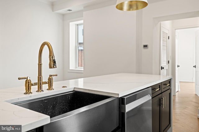 kitchen featuring a sink, dark cabinetry, light stone countertops, and dishwasher