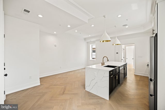 kitchen featuring baseboards, open floor plan, a center island with sink, a sink, and appliances with stainless steel finishes
