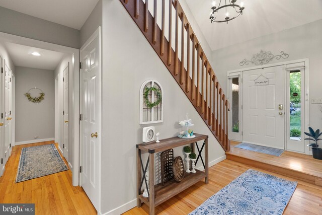 entrance foyer with an inviting chandelier, baseboards, stairs, and wood finished floors