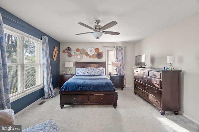 bedroom featuring baseboards, multiple windows, and light carpet