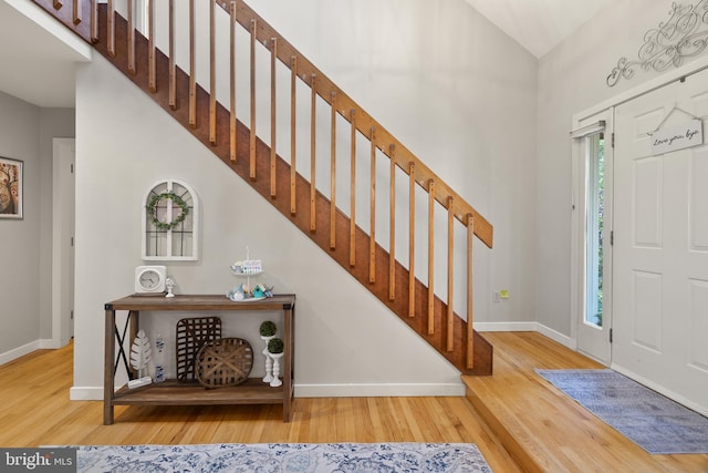 foyer entrance with baseboards, stairs, and wood finished floors