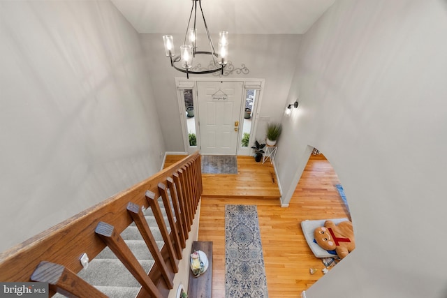 entrance foyer with stairs, baseboards, an inviting chandelier, and wood finished floors