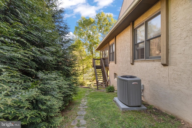 view of side of home featuring stucco siding, central air condition unit, and stairs