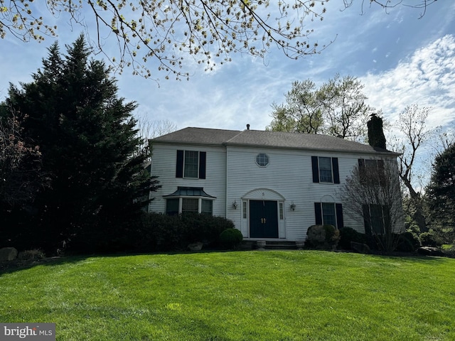 colonial house with a front yard and a chimney
