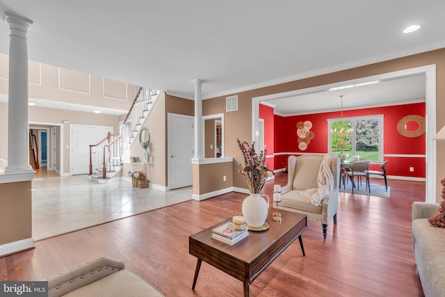 living room featuring decorative columns, visible vents, wood finished floors, baseboards, and ornamental molding
