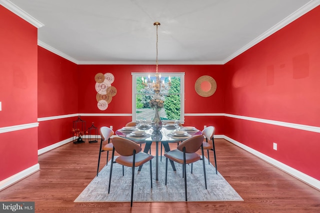 dining space with baseboards, ornamental molding, wood finished floors, and a chandelier