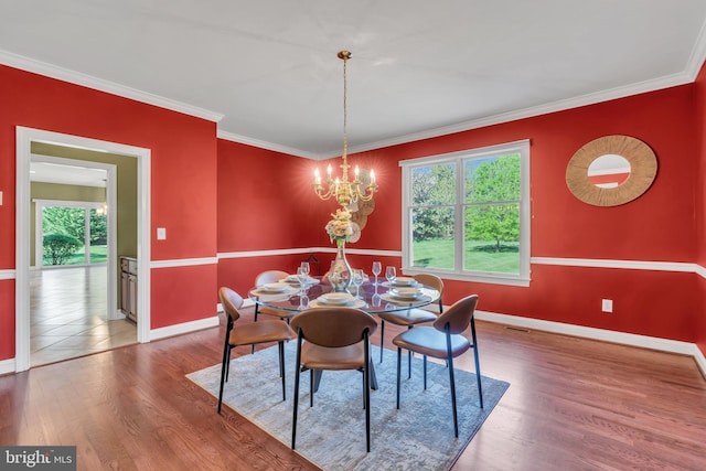 dining room featuring plenty of natural light, ornamental molding, baseboards, and wood finished floors