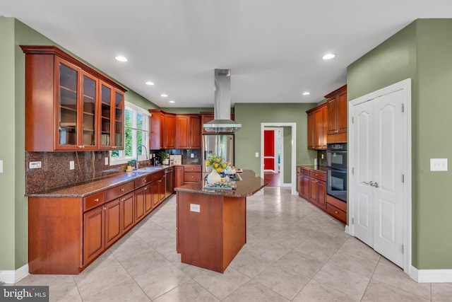 kitchen with a kitchen island, baseboards, island range hood, backsplash, and stainless steel appliances