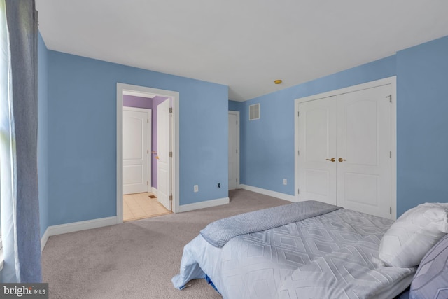 carpeted bedroom with baseboards, ensuite bathroom, a closet, and visible vents