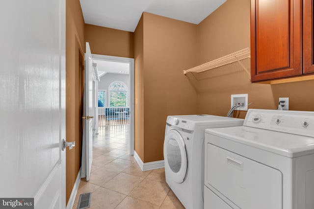 laundry area featuring visible vents, washing machine and dryer, light tile patterned flooring, baseboards, and cabinet space