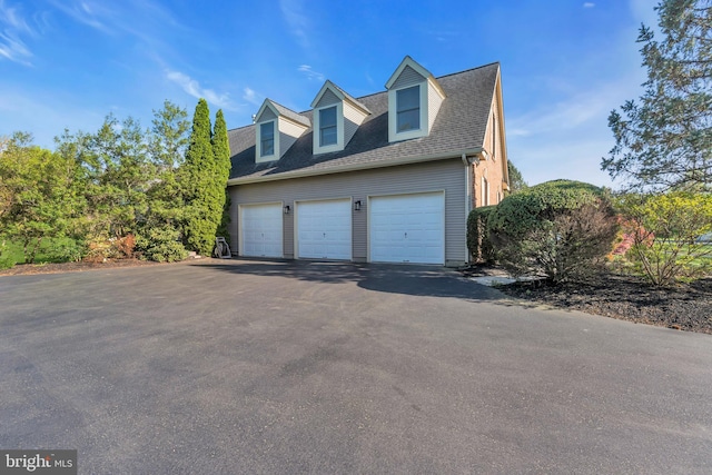 view of home's exterior with driveway, a shingled roof, and a garage