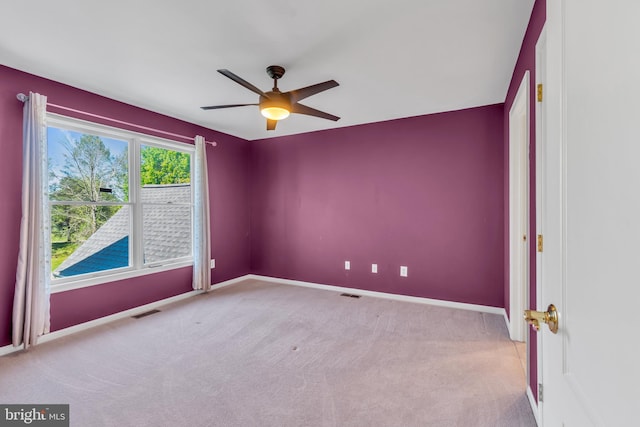 spare room featuring carpet floors, ceiling fan, visible vents, and baseboards