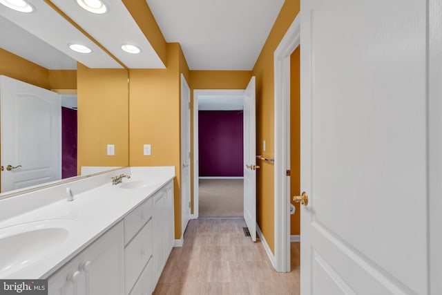 bathroom featuring a sink, baseboards, recessed lighting, and double vanity