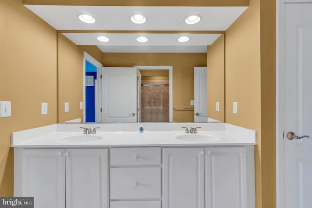 bathroom featuring double vanity, walk in shower, and a sink