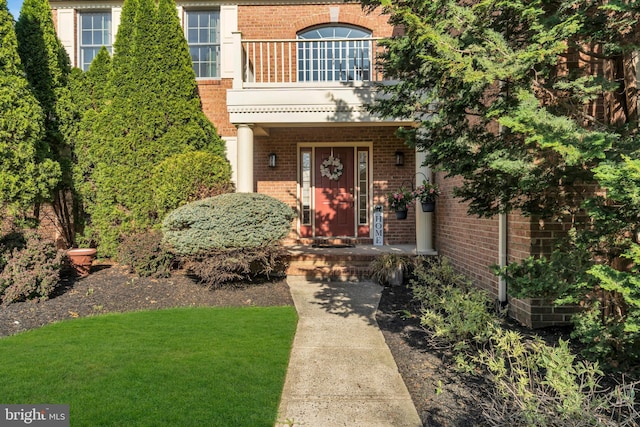 entrance to property with brick siding and a lawn
