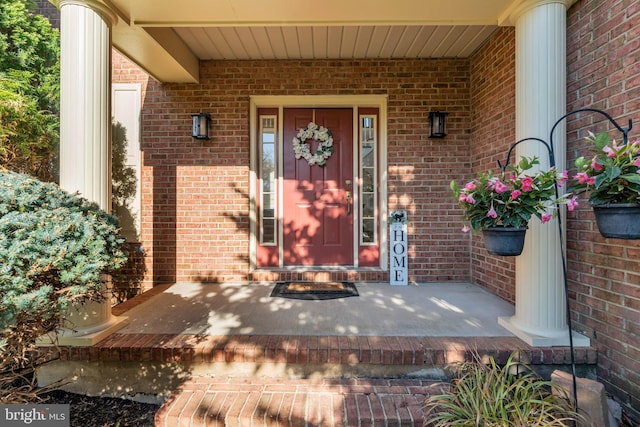 entrance to property featuring covered porch and brick siding