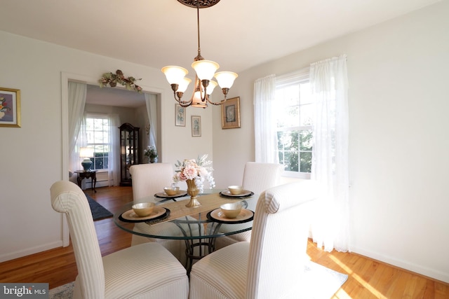 dining room with baseboards, light wood finished floors, and a notable chandelier