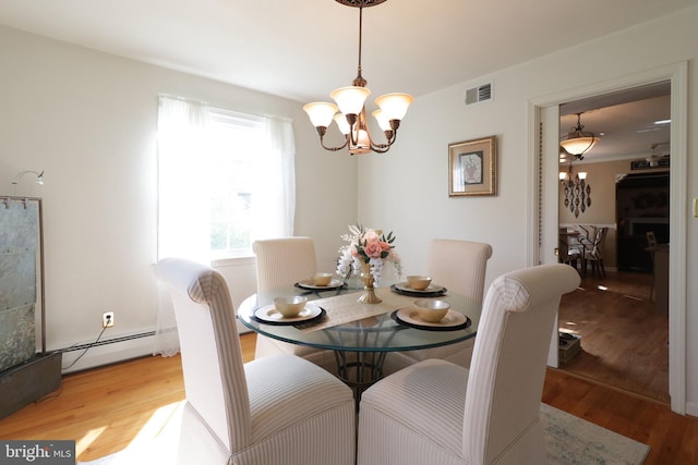 dining space with a notable chandelier, light wood-style flooring, visible vents, and a baseboard radiator