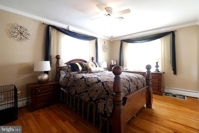 bedroom with crown molding, visible vents, a ceiling fan, wood finished floors, and a baseboard heating unit