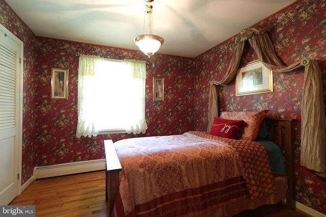 bedroom featuring wood finished floors, baseboards, and a baseboard heating unit