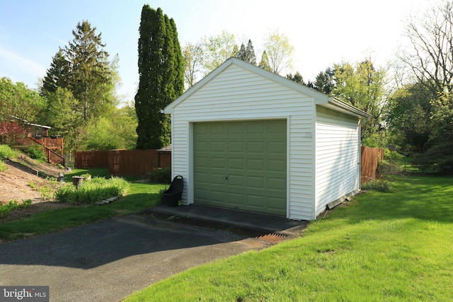 detached garage featuring fence and driveway