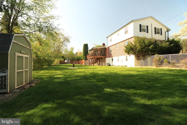 view of yard featuring fence, a storage unit, and an outbuilding
