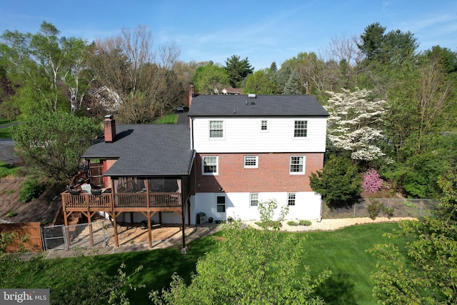 back of house with a chimney, a lawn, a deck, a sunroom, and a fenced backyard
