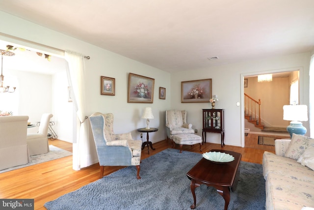 living area featuring stairway, visible vents, wood finished floors, and a chandelier