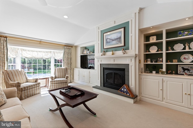 carpeted living area featuring built in features, a fireplace with raised hearth, and lofted ceiling
