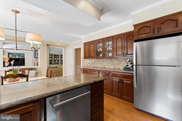 kitchen featuring hanging light fixtures, appliances with stainless steel finishes, decorative backsplash, ornamental molding, and glass insert cabinets