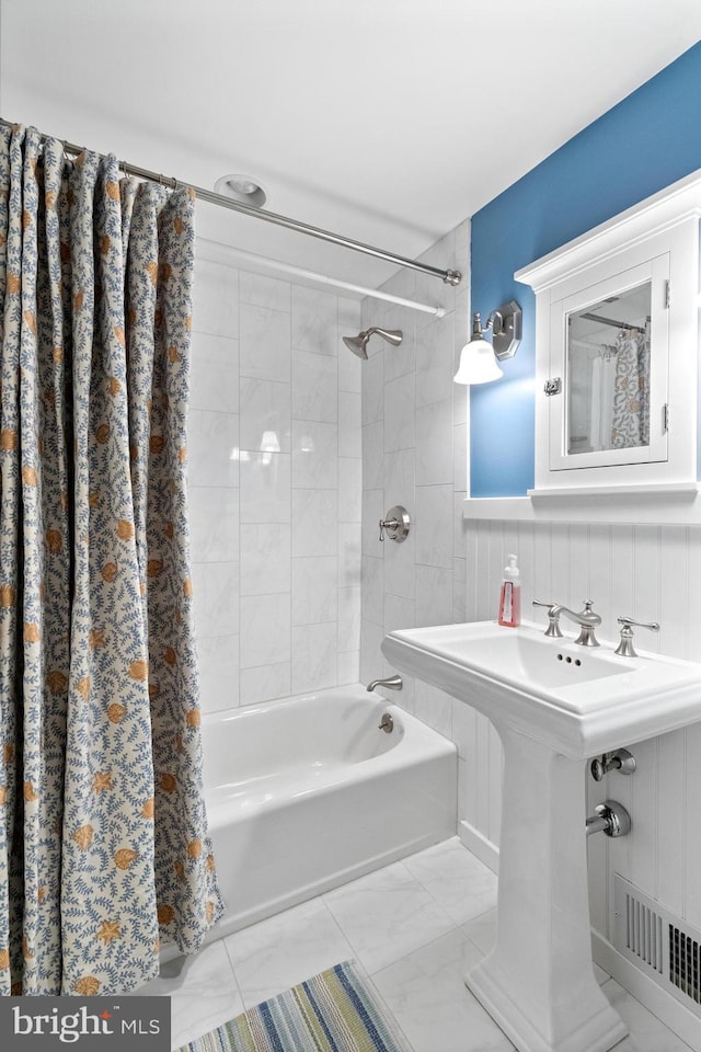 bathroom with a sink, shower / tub combo with curtain, marble finish floor, and visible vents