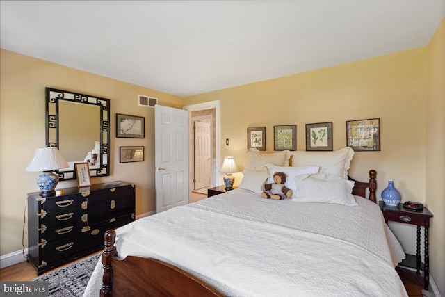 bedroom featuring baseboards, visible vents, and wood finished floors